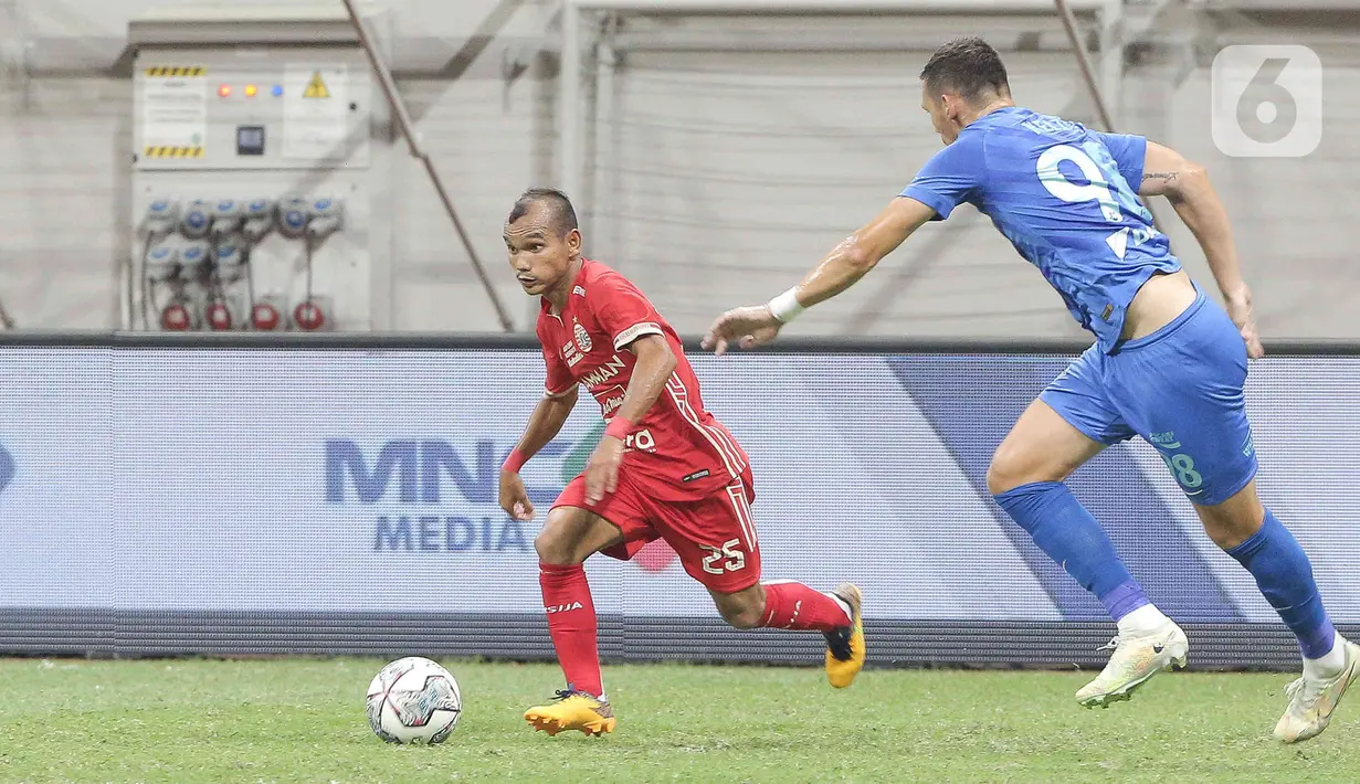 Pesepak bola Persija Jakarta Riko Simanjuntak (kiri) berusaha melewati pesepak bola Chonburi FC pada laga persahabatan dalam rangka peresmian Stadion Jakarta International Stadium (JIS) di Jakarta, Minggu (24/7/2022). Pertandingan berakhir imbang dengan skor 3-3. (Liputan6.com/Herman Zakharia)