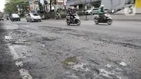 Kendaraan melintas dekat jalan berlubang di kawasan Kelapa Gading, Jakarta, Minggu (1/3/2020). Kepala Dinas Bina Marga DKI Jakarta Hari Nugroho mengatakan banjir pada Februari 2020 merusak 495 jalan Ibu Kota dengan 3.290 titik lubang yang tersebar di lima wilayah. (merdeka.com/Iqbal Nugroho)