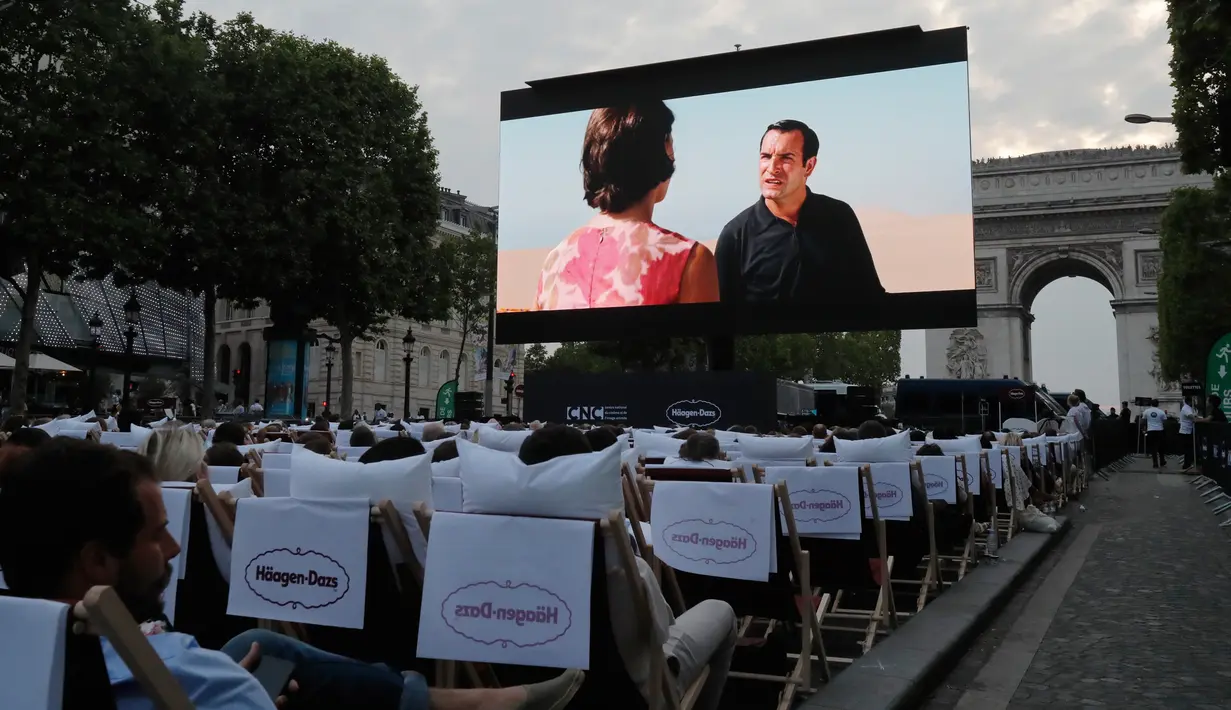 Sebuah film gratis yang diputar di ruang terbuka di jalan Champs Elysees, Paris (7/7/2019). Bioskop terbuka ini menyediakan 1800 kursi bagi penonton yang ingin menyaksikan film-film gratis yang ditayangkan. (AP Photo/Michel Euler)