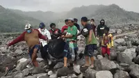 Tim penyelamat dan warga membawa kantong jenazah berisi jenazah korban letusan Gunung Semeru, di Desa Candi Puro, Lumajang, Jawa Timur, Selasa (7/12/2021). (AP Photo/Rokhmad)