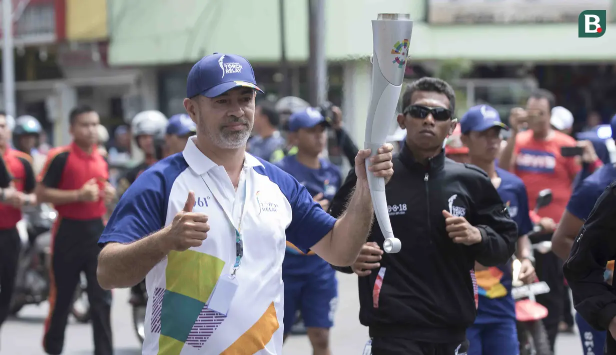 Pevoli legendaris Indonesia, Pascal Wilmar, berlari saat pawai obor Asian Games XVIII di Palembang, Sumatra Selatan, Sabtu (4/8/2018). Sebanyak 53 kota di Indonesia akan dilalui oleh obor Asian Games. (Bola.com/Reza Bachtiar)