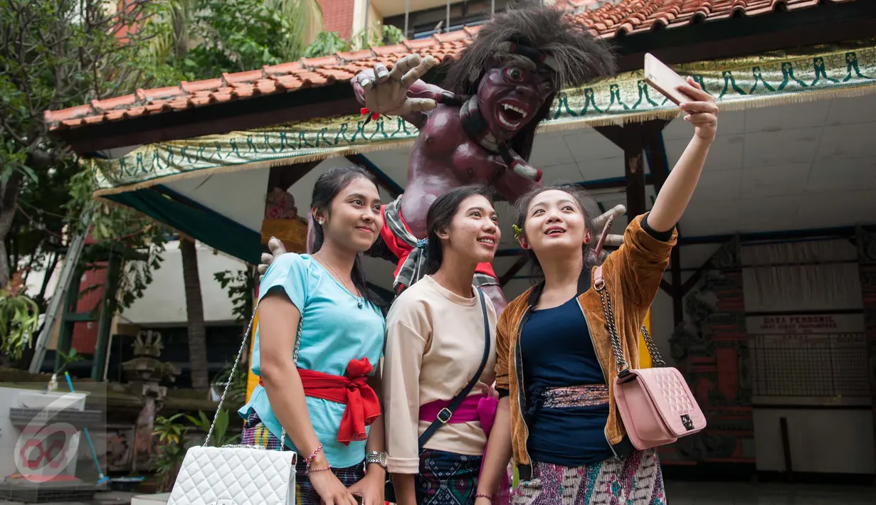 Umat Hindu berswafoto dengan Ogoh-ogoh di Pura Agung Wira Satya Buana, Jakarta, Senin (27/3). Umat Hindu akan merayakan hari raya Nyepi Tahun Baru Saka 1939 yang jatuh pada tanggal 28 Maret 2017. (Liputan6.com/Gempur M. Surya)