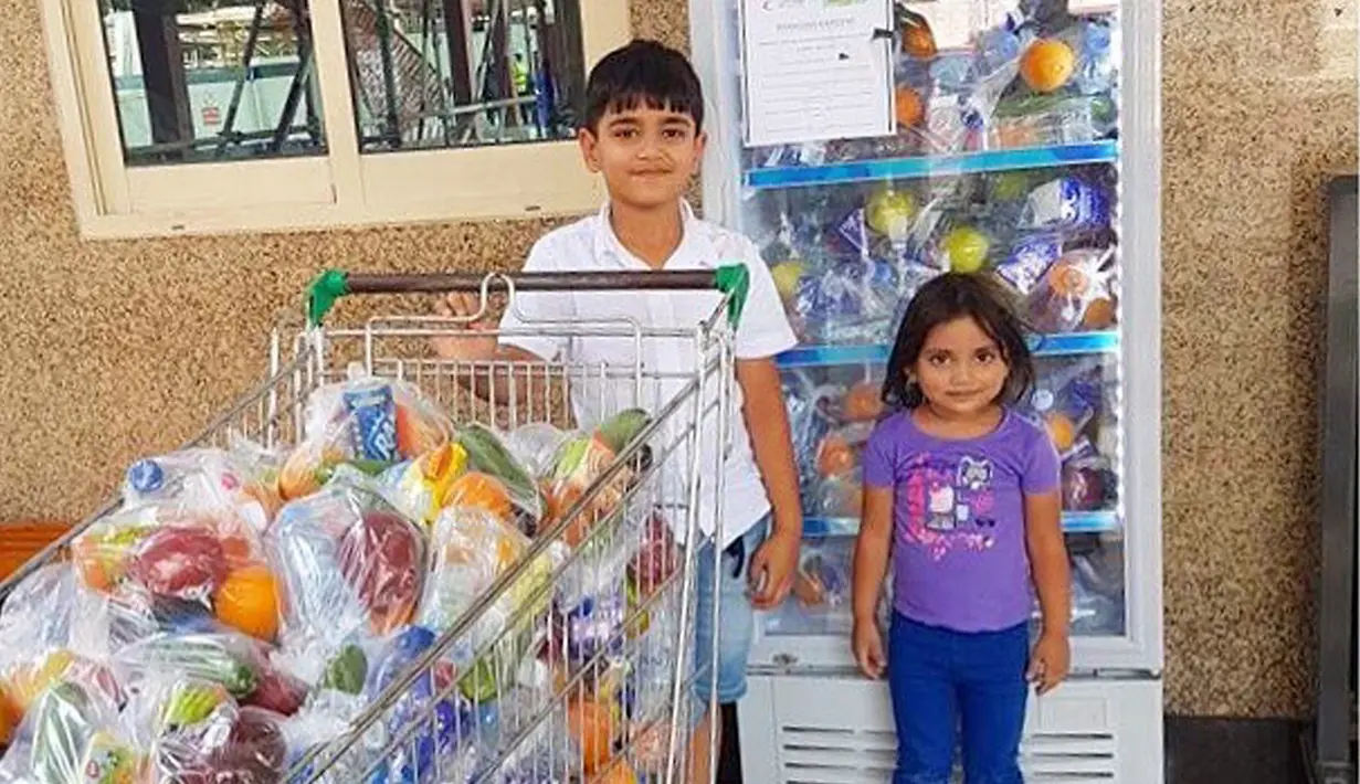 Dua orang anak berfoto di depan kulkas dan trolli yang berisi makanan dan minuman jelang bulan Ramadan di Dubai. Makanan dan minuman untuk berbuka puasa ini disediakan gratis untuk pekerja dan buruh. (www.instagram.com/ramadanfridgesdxb)