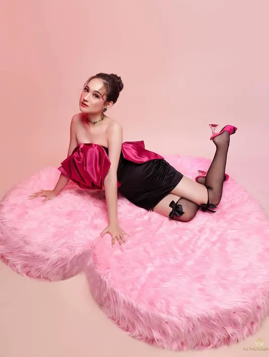 Di sebuah photoshoot, Laura Moane tampil menawan bak boneka Barbie. Ia mengenakan strapless mini dress dengan bagian atasnya berbentuk pita berwarna pink dengan rok velvet hitam. Penampilan Laura semakin manis dengan stoking hitam transparan dan kitten open toe heels pink yang serasi. [Foto: Instagram/its_lauramoane2]