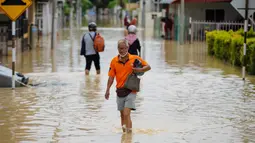 Warga mengarungi banjir di Batu Berendam, Malaka, Malaysia, 3 Januari 2022. Dilaporkan AsiaOne, Selasa (4/1/2022) ada tujuh negara bagian Malaysia yang terdampak, yakni Kelantan, Terengganu, Pahang, Johor, Malacca, Negeri Sembilan dan Sabah. (NAZRULHAD HASHIM/AFP)