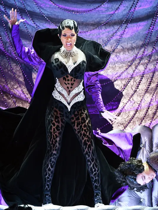 Penyanyi Rapper Cardi B tampil membawakan lagu "Money" di atas panggung Grammy Awards 2019 yang digelar di Staples Center, Los Angeles, Minggu (10/2). Penampilannya sangat seksi dengan latar panggung bewarna ungu gelap. (Kevin Winter/Getty Images/AFP)