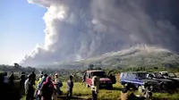 Orang-orang menyaksikan Gunung Sinabung memuntahkan material vulkanik saat meletus di Karo, Sumatera Utara, Selasa (2/3/2021). Gunung berapi setinggi 2.600 meter (8.530 kaki) itu meletus Selasa, mengirimkan material vulkanik beberapa ribu meter ke langit. (AP Photo)