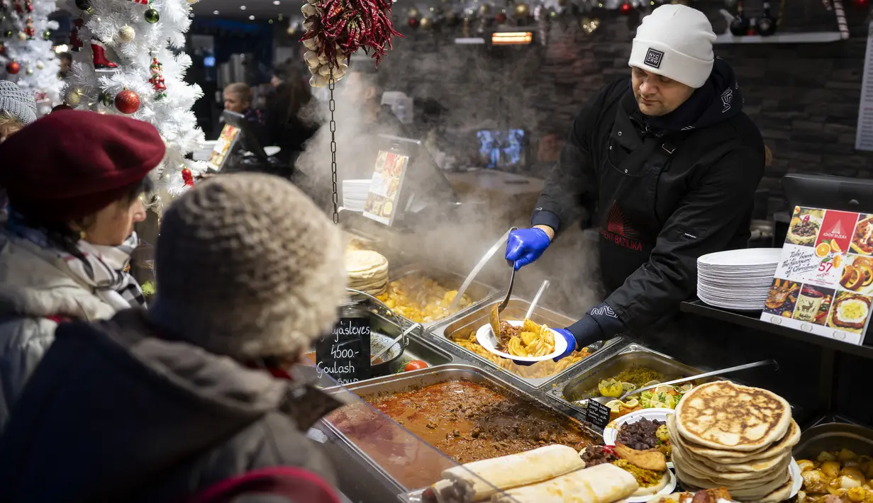 Seorang pekerja melayani pelanggan di pasar Advent Bazilika, salah satu pasar Natal luar ruangan paling terkenal di Eropa di pusat kota Budapest, Hungaria, Sabtu, 9 Desember 2023. (AP Photo/Denes Erdos)