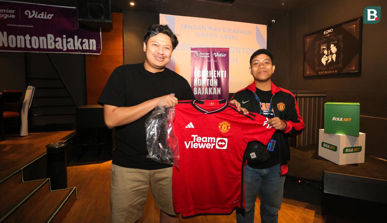 Seorang penonton mendapatkan hadiah berupa jersey home original Manchester United pada acara Roaring Night antara Manchester United melawan West Ham yang berlangsung di Fomo Bar, Melawai, Jakarta, Minggu (04/02/2024) malam WIB. (Bola.com/Bagaskara Lazuardi)