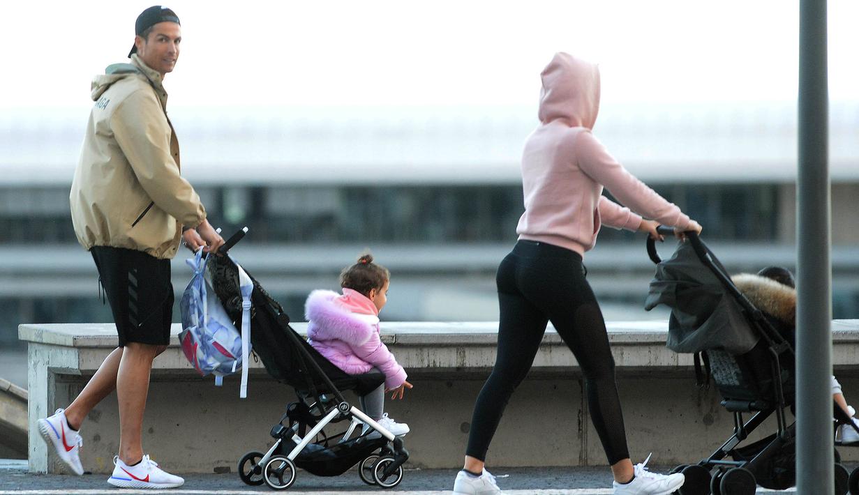 Cristiano Ronaldo bersama kekasihnya Georgina Rodriguez mengajak anak-anaknya berjalan santai di Funchal, Portugal, Sabtu (28/3/2020). Bintang Juventus ini memilih pulang kampung saat Serie A dihentikan sementara karena wabah virus corona. (AFP/Helder Santos)
