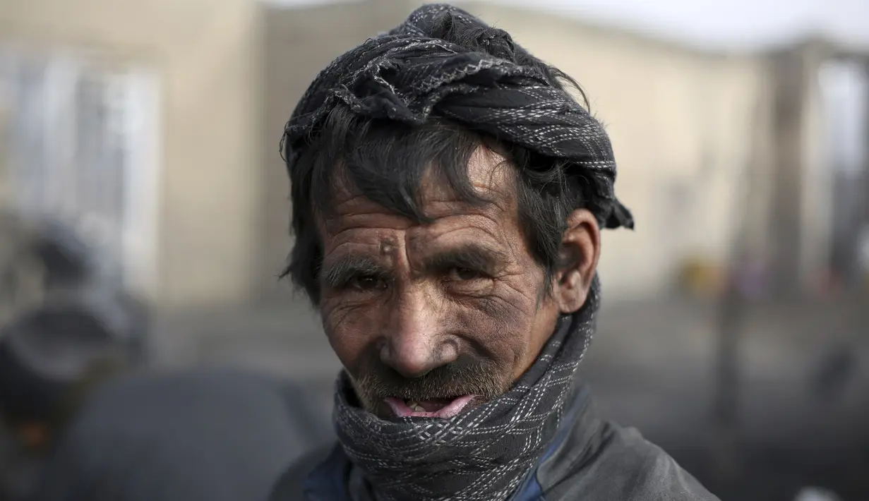Seorang buruh Afghanistan berpose ketika ia bekerja di pasar arang di pinggiran Kabul, Afghanistan (18/12/2019). Di musim dingin, harga kayu dan arang naik di antara semua kebutuhan lain untuk warga Afghanistan. (AP Photo / Rahmat Gul)