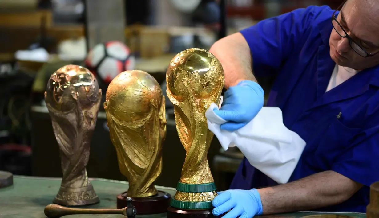 Pekerja membersihkan dengan kain replika trofi Piala Dunia FIFA di piala Italia dan pabrikan medali GDE Bertoni di Paderno Dugnano, Milan (11/4). Piala Dunia akan diselenggarakan 14 Juni sampai 15 Juli di Rusia. (AFP Photo/Miguel Medina)