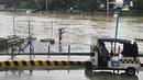 Seorang pria memotret sungai yang meluap akibat curah hujan yang meningkat akibat Topan Doksuri di kota Marikina, Filipina pada Kamis, 27 Juli 2023. (AP Photo/Aaron Favila)