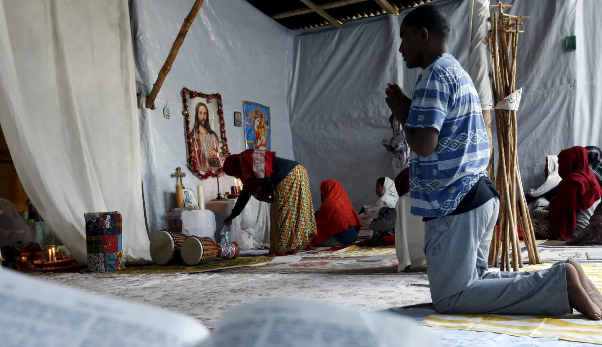 Seorang imigran gelap tampak berdoa ketika mengikuti misa di gereja darurat di sekitar pelabuhan Calais, Prancis, Minggu (2/8/2015). Sebelumnya ratusan imigran memaksa masuk Prancis melalui Terowongan Channel. (REUTERS/Pascal Rossignol)