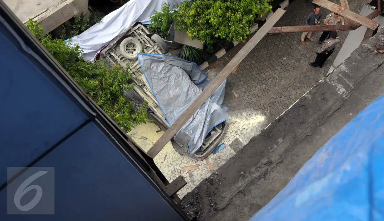 Sebuah mobil Toyota Kijang warna merah marun ditutupi terpal setelah jatuh dari lantai 3 Gedung Migas, Jakarta, Selasa (5/4). Mobil yang terjatuh itu berasal dari lantai 3 yang diketahui merupakan lokasi parkir. (Liputan6.com/Helmi Affandi)