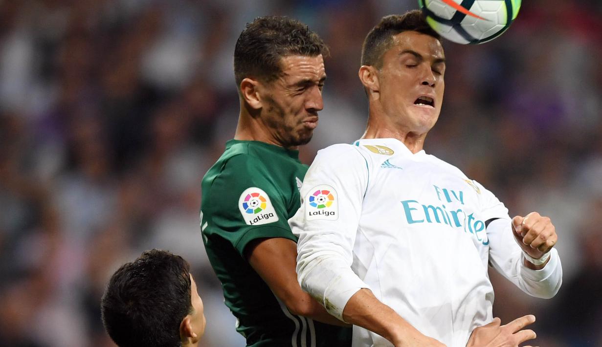 Striker Real Madrid, Cristiano Ronaldo, duel udara dengan bek Real Betis, Morocco Zou pada laga La Liga Spanyol di Stadion Santiago Bernabeu, Rabu (20/9/2017). Real Madrid kalah 0-1 dari Real Betis. (AFP/Gabriel Bouys)