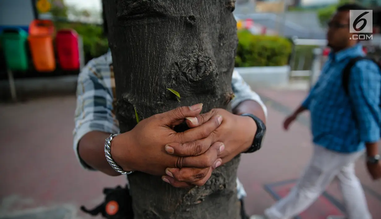 Massa dari Koalisi Pejalan Kaki, KPBB, dan Thamrin School of Climate Change and Sustainability menggelar aksi #ayopelukpohonini di Jalan Sudirman, Jakarta, Jumat (22/9). (Liputan6.com/Faizal Fanani)