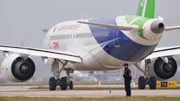 Petugas berdiri dekat pesawat penumpang jet C919 jelang penerbangan perdana di Bandara Internasional Pudong, Jumat (5/5). C919 adalah buatan Commercial Aircraft Corporation of China (COMAC) yang merupakan milik pemerintah. (Aly Song/Pool Photo via AP)