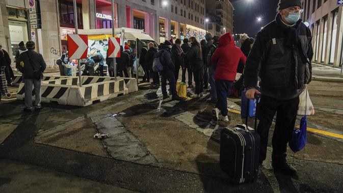Giovanni Petazzi dengan bawaannya antre makanan gratis di truk makanan Progetto Arca di pusat kota Milan, Italia, 10 Desember 2020. Tidak ada tempat di Italia yang kemiskinan lebih jelas daripada di Lombardy, wilayah utara yang sempat menjadi episentrum penularan COVID-19. (AP Photo/Luca Bruno)