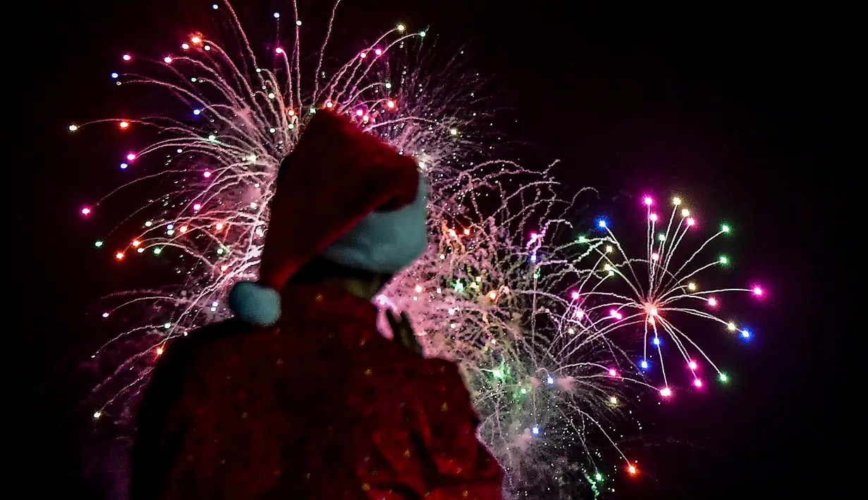 Seorang pria mengenakan kostum santa melihat kembang api selama parade Natal di Panama City (16/12). Warga Panama tengah mempersiapkan diri menyambut datangnya Natal 2018 yang jatuh pada tanggal 25 Desember. (AFP Photo/Luis Acosta)