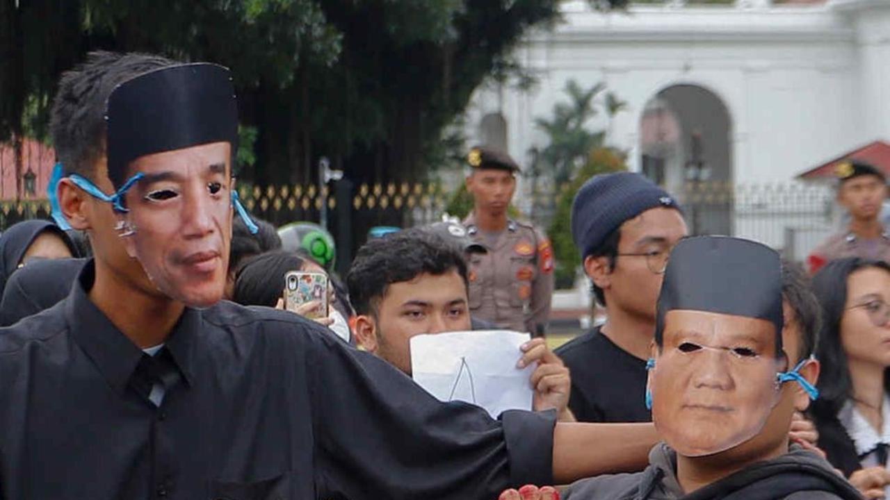 Aktivis Jaringan Solidaritas Korban untuk Keadilan memakai topeng Jokowi dan Prabowo saat mengikuti aksi Kamisan Ke-807 di seberang Istana Merdeka, Jakarta, Kamis (29/2/2024). Foto: Liputan6.com / Herman Zakharia