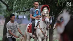 Seorang pria bersama anaknya menunggangi kuda saat menunggu waktu berbuka puasa atau ngabuburit di kawasan Kanal Banjir Timur, Jakarta, Selasa (5/6). Warga cukup mengeluarkan uang sebesar Rp 10 ribu untuk menaiki kuda. (Merdeka.com/Iqbal S. Nugroho)