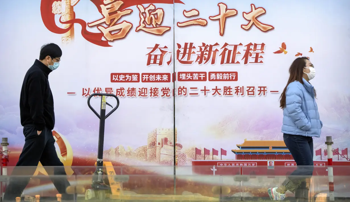 Orang-orang melewati papan reklame yang menandai Kongres Nasional ke-20 Partai Komunis China yang akan datang, di Beijing, Selasa (11/10/2022). Penguncian terbaru dimulai Senin lalu di kota Fenyang di provinsi Shanxi China utara setelah kasus positif awal ditemukan dalam pengujian di seluruh kota pada hari sebelumnya. (AP Photo/Mark Schiefelbein)