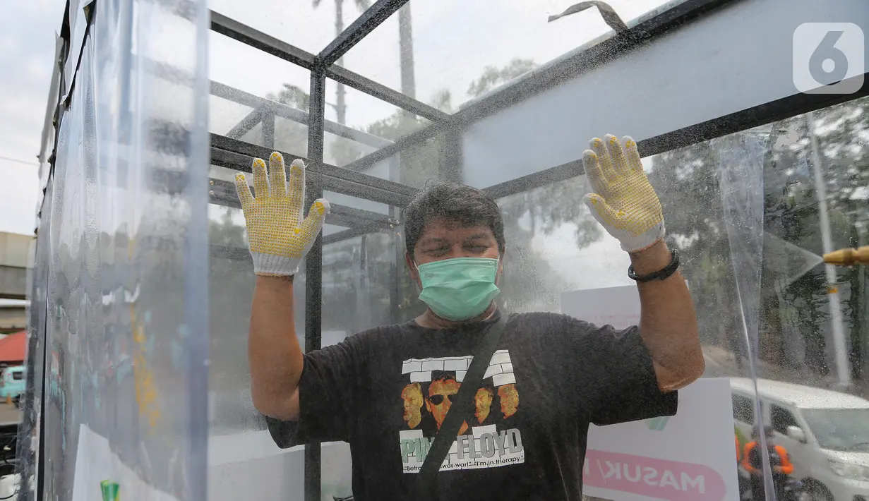Warga menyemprotkan diri menggunakan cairan antiseptik di disinfektan chamber di CheCk Point PSBB, perbatasan Jakarta - Tangerang Selatan, Pasar Jumat, Kamis (16/4/2020). Disinfektan chamber tersebut juga diperuntukan bagi petugas dan penumpang angkutan umum. (Liputan6.com/Fery Pradolo)