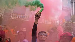 Seorang buruh mengangkat tongkat asap selama unjuk rasa Hari Buruh Internasional (May Day) di Jakarta, Indonesia, Senin (1/5/2023). (AP Photo/Dita Alangkara)