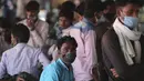 Buruh migran yang memakai masker sebagai antisipasi terhadap virus corona menunggu pengangkutan di terminal bus di Jammu, India(26/3/2021). Pihak berwenang di kota Mumbai mengatakan mereka akan menggelar tes virus korona acak wajib di tempat-tempat ramai. (AP Photo/Channi Anand)