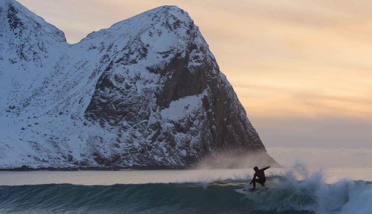 Seorang peselancar tengah beraksi di kawasan pantai  Flackstad, dekat Ramberg, kepulauan Lofoten, Arctic Circle, (9/3/2016). (AFP/Olivier Morin)