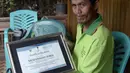 Muhammad Idris, salah satu pelopor antirokok menunjukkan sertifikat atas usahanya menjadikan Desa Bone-Bone, Sulawesi Selatan, bebas asap rokok, 20 Desember 2015. Bagi yang melanggar aturan larangan merokok, diberikan sanksi kerja sosial (Cening Unru/AFP)