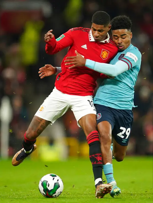 Pemain Manchester United Marcus Rashford (kiri) berebut bola dengan pemain Burnley Ian Maatsen pada pertandingan sepak bola putaran keempat Piala Liga Inggris di Old Trafford, Manchester, Inggris, 21 Desember 2022. (AP Photo/Dave Thompson)