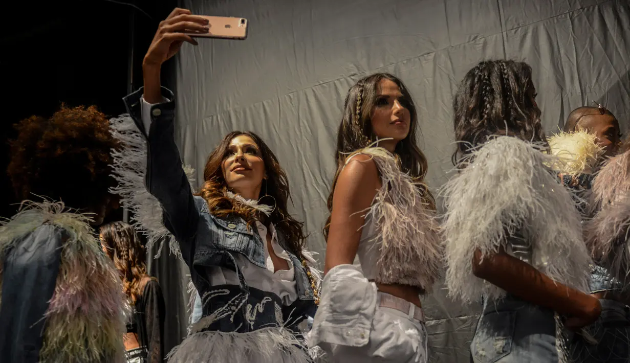 Seorang model berselfie di belakang panggung sebelum tampil membawakan busana Jay Star Jeans di Colombiamoda sebagai bagian dari Colombia Fashion Week di Medellin, Departemen Antioquia, Kolombia (25/7). (AFP Photo/Joaquin Sarmiento)