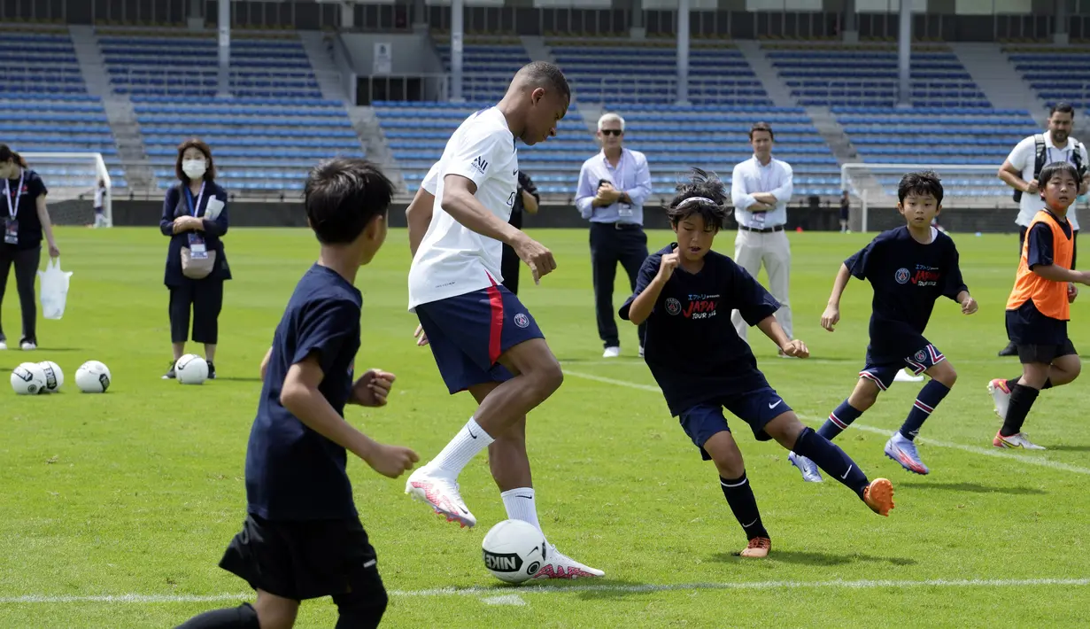 Pemain sepak bola Paris Saint-Germain (PSG) Kylian Mbappe bermain sepak bola dengan anak-anak saat melakukan pelatihan di Tokyo, Jepang, 18 Juli 2022. PSG berada di Jepang untuk tur pra-musim mereka dan akan memainkan tiga pertandingan persahabatan melawan tim Liga Jepang. (AP Photo/Eugene Hoshiko)