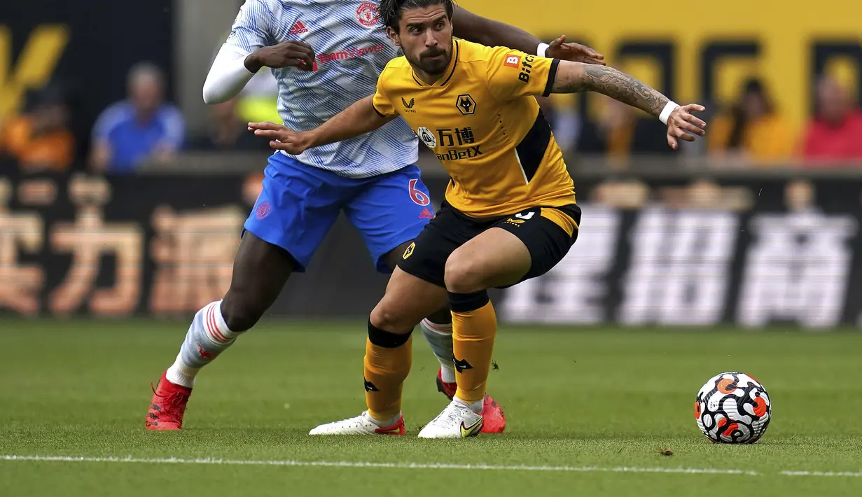 Gelandang Manchester United (MU) Paul Pogba berebut bola dengan gelandang Wolverhampton Wanderers Ruben Neves pada match day ketiga Liga Inggris di Stadion Molineux, Minggu (29/8/2021). MU menang tipis 1-0 lewat gol Mason Greenwood. (Nick Potts/PA via AP)