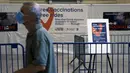 Seorang pria melewati informasi vaksinasi di Grand Central Terminal, New York City, Selasa (27/7/2021). Warga Amerika yang divaksinasi penuh harus kembali memakai masker di dalam ruangan di tempat-tempat di mana corona dan terutama varian Delta menyebar dengan cepat. (Spencer Platt/Getty Images/AFP)