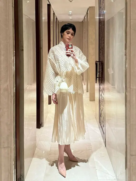 Renata Kusmanto kenakan busana off white yang iapdukan atasan berjaring dengan pleated skirt midi metalik. Ia kenakan sling bag dari Simona Rocha yang ikonik [@renata711]