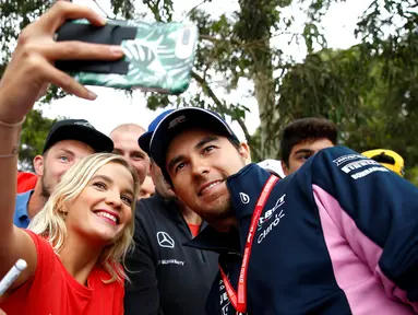 Pembalap F1 Racing Point, Sergio Perez berselfie dengan penggemarnya saat tiba di Sirkuit Melbourne Grand Prix di Melbourne, Jumat (15/3). Seri GP Australia akan menjadi pembuka ajang Formula 1 (F1) musim 2019. (Reuters/Edgar Su)