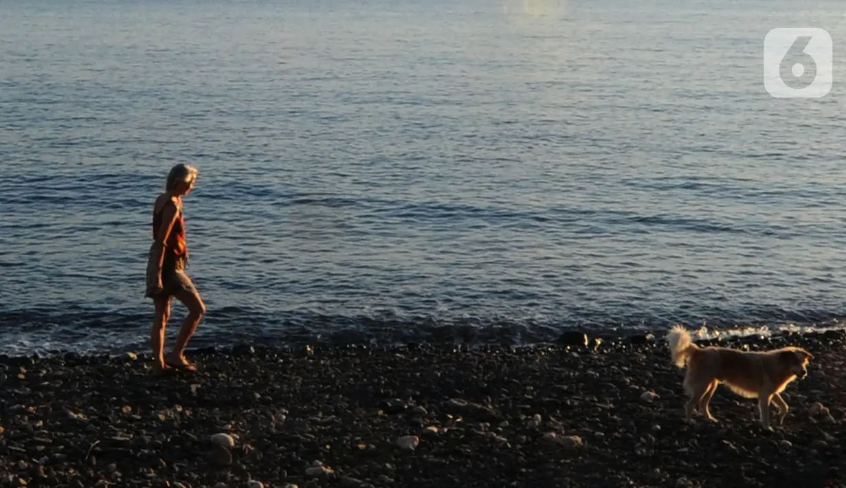 Wisatawan menikmati pemandangan di kawasan Pantai Amed, Bali, Jumat (3/9/2021). Sepinya wisatawan yang datang ke Pulau Bali selama PPKM Darurat yakni hanya sebesar rata-rata 500 wisatawan lokal menyebabkan sejumlah tempat wisata pantai sepi pengunjung. (merdeka.com/Arie Basuki)