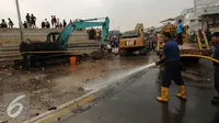 Petugas Damkar menyemprotkan air membersihkan Jalan Jatinegara Barat dari sisa material saat terjadi kerusuhan jelang proses penggusuran warga yang tinggal di Kampung Pulo, Jakarta, Kamis (20/8/2015). (Liputan6.com/Helmi Fithriansyah)