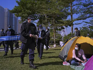Petugas polisi membawa spanduk yang menunjukkan jarak sosial untuk mencegah penyebaran virus corona kepada pengunjung di sebuah taman di Hong Kong, Sabtu (2/1/2021). Diketahui, varian baru virus corona Inggris ditemukan di Hong Kong. (AP Photo/Vincent Yu)