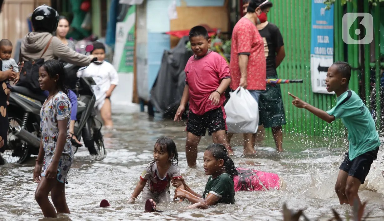 Anak anak bermain air di sebagian Jalan Bungur Besar Raya yang tergenang, Jakarta, Selasa (18/1/2022). Genangan air di sebagian Jalan Bungur Besar Raya dimanfaatkan anak-anak untuk bermain meski berbahaya. (Liputan6.com/Helmi Fithriansyah)