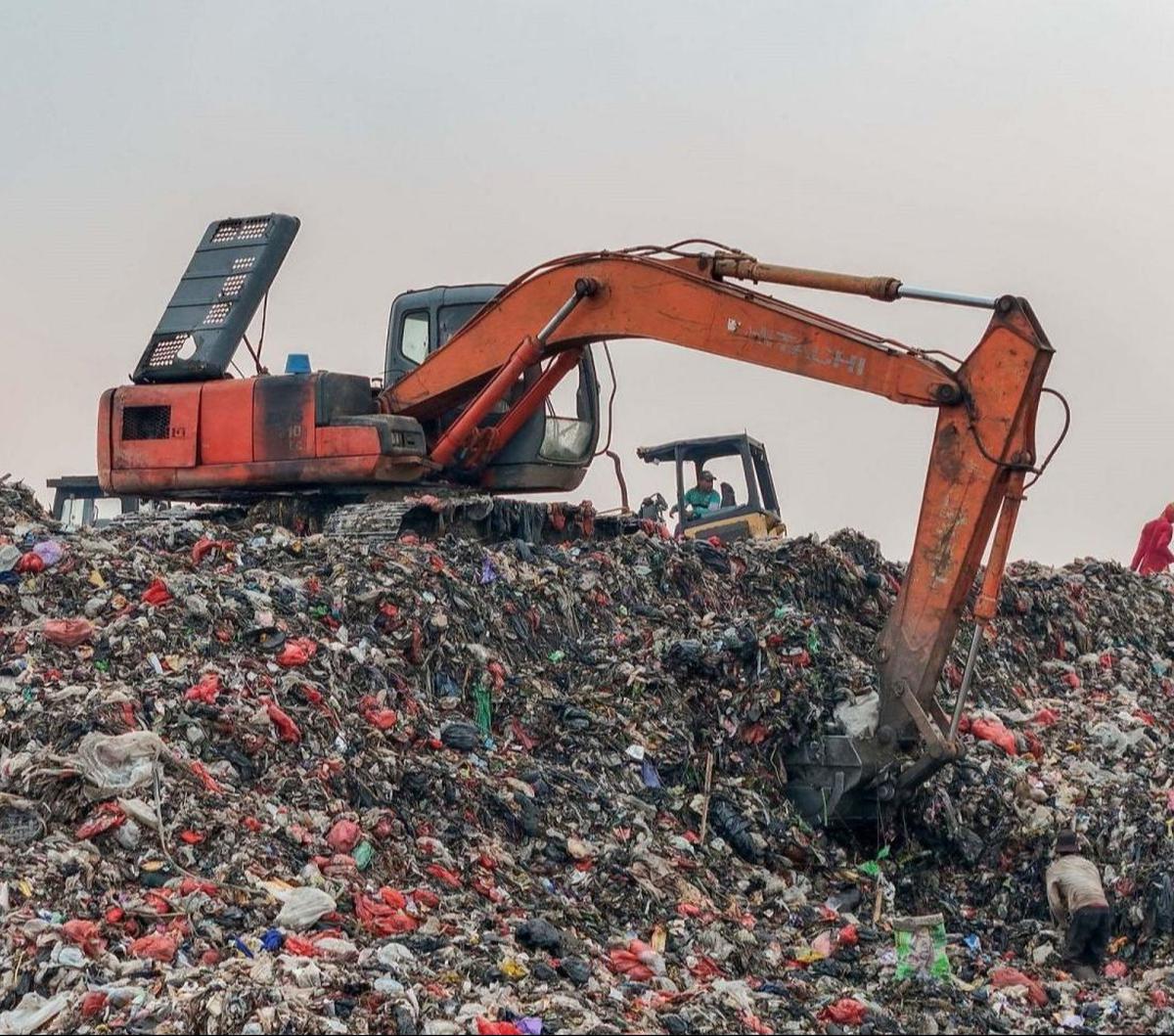 Sebuah alat berat eskavator beroperasi untuk mengurangi tumpukan sampah yang menggunung di lokasi pembuangan sampah TPA Cipayung, Depok, Jawa Barat, Selasa (07/5/2024). Foto: merdeka.com / Arie Basuki