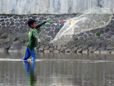 Seorang anak menjala ikan di area Bendung Katulampa, Kota Bogor, Jawa Barat, Senin (3/8/2020). Debit air sungai Ciliwung di Bendung Katulampa yang mengalami penyusutan sejak satu bulan terakhir dimanfaatkan anak-anak untuk bermain air dan layangan. (Liputan6.com/Helmi Fithriansyah)