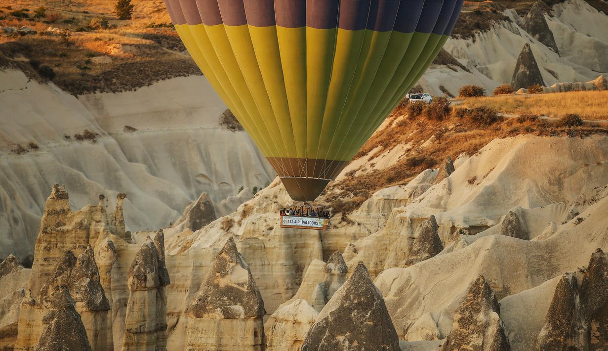 Balon udara membawa wisatawan naik ke langit saat matahari terbit di Kapadokia, Turki, Selasa (7/8). Cerobong Peri Kapadokia adalah lansekap batu vulkanik berbentuk kerucut yang menjulang tinggi ke langit. (AP Photo/Emrah Gurel)