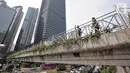 Pejalan kaki melintas di jembatan penyeberangan orang (JPO) yang tidak beratap di jalan Sudirman, Jakarta, Rabu (6/11/2019). Pemprov DKI melalui Dinas Bina Marga mencopot atap JPO Sudirman agar pejalan kaki dapat menikmati pemandangan gedung-gedung pencakar langit. (merdeka.com/Iqbal Nugroho)