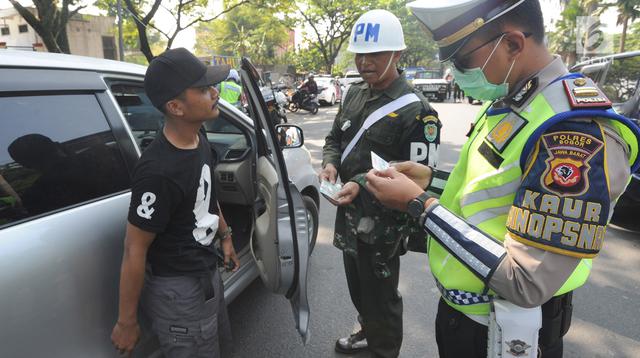 Petugas kepolisian memeriksa kelengkapan dokumen pengendara mobil saat melakukan razia gabungan di kawasan Naggewer,  Bogor, Selasa (18/9). Razia rutin itu melibatkan unsur Polri dengan Dispenda, POM TNI dan Dinas Perhubungan. (Merdeka.com/Arie Basuki)