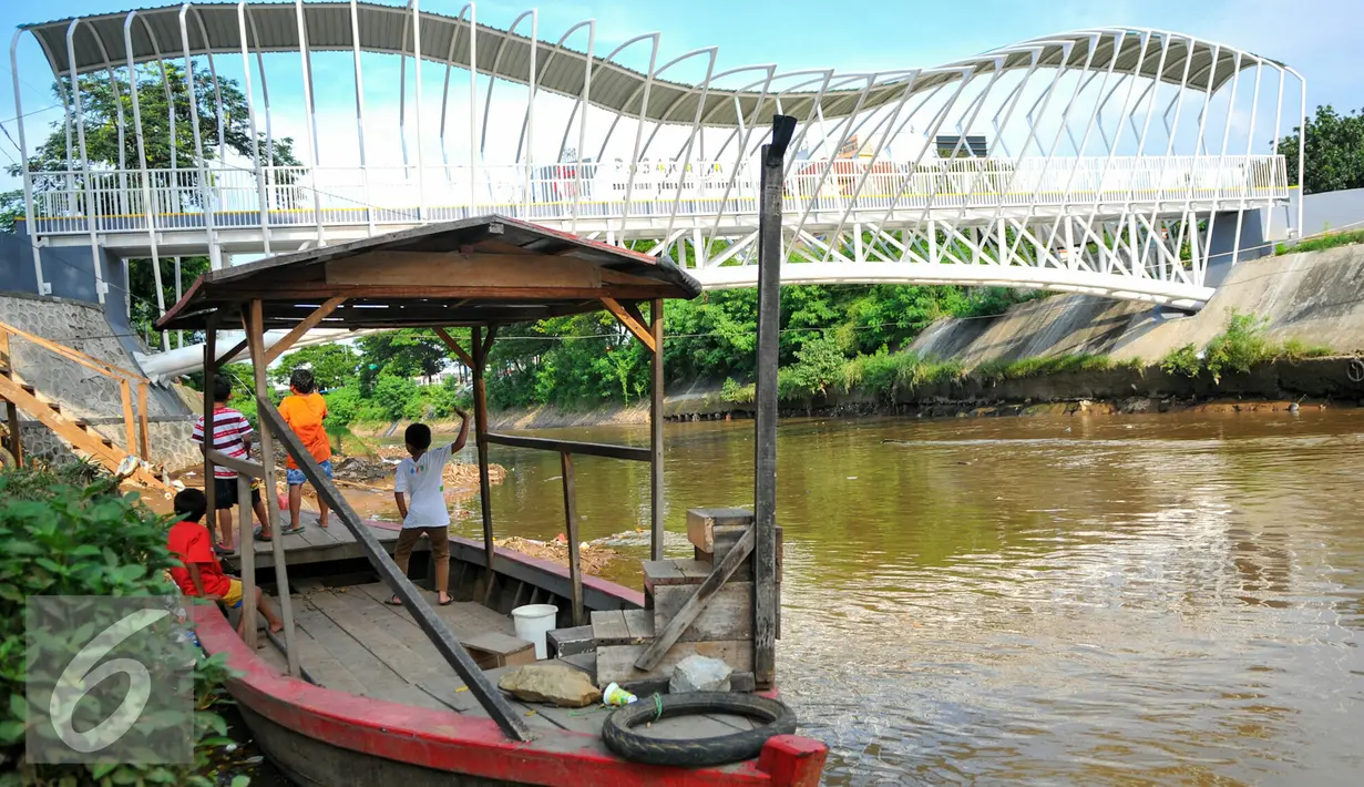 Sejumlah anak  bermain di atas perahu eretan yang kini tidak beroperasi lagi, Jakarta, Kamis (28/4/2016). Kehadiran JPO di atas sungai Ciliwung mempermudah warga untuk menyeberang dan meninggalkan transportasi perahu eretan. (Liputan6.com/Yoppy Renato)