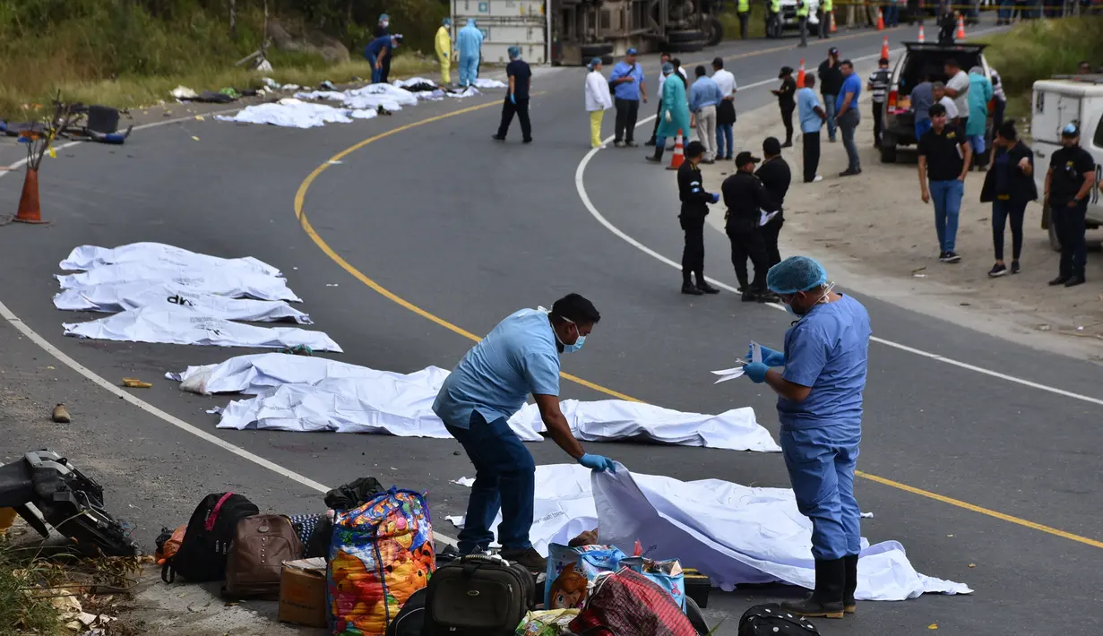Tim forensik menutupi tubuh penumpang yang tewas dalam kecelakaan bus yang menabrak truk trailer di Gualan, Guatemala (21/12/2019). Kecelakaan tersebut menewaskan sedikitnya 21 orang dan menyebabkan belasan orang luka-luka. (AP Photo/Carlos Cruz)